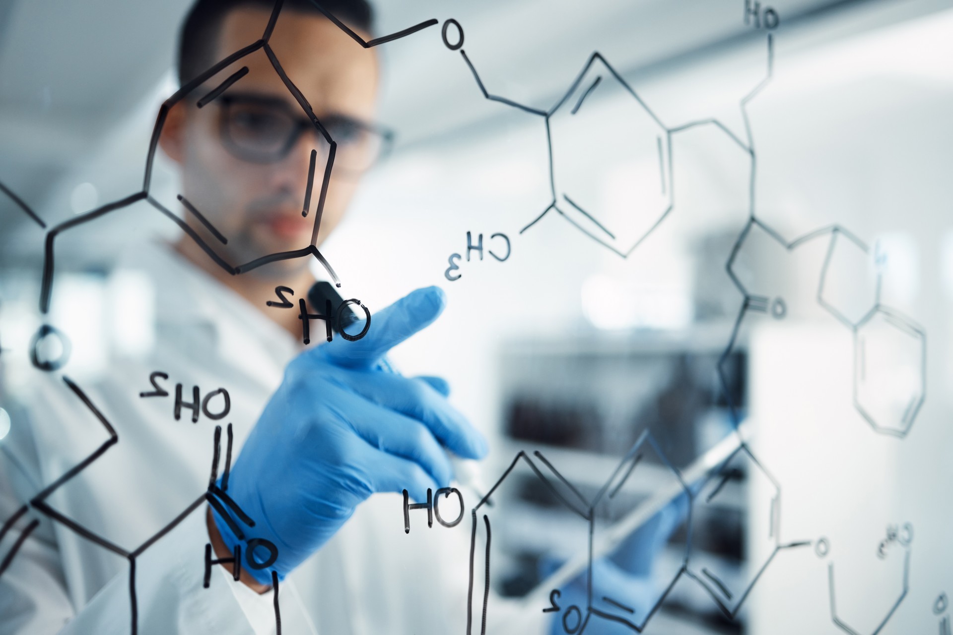 Shot of a young scientist solving equations on a glass screen in a laboratory